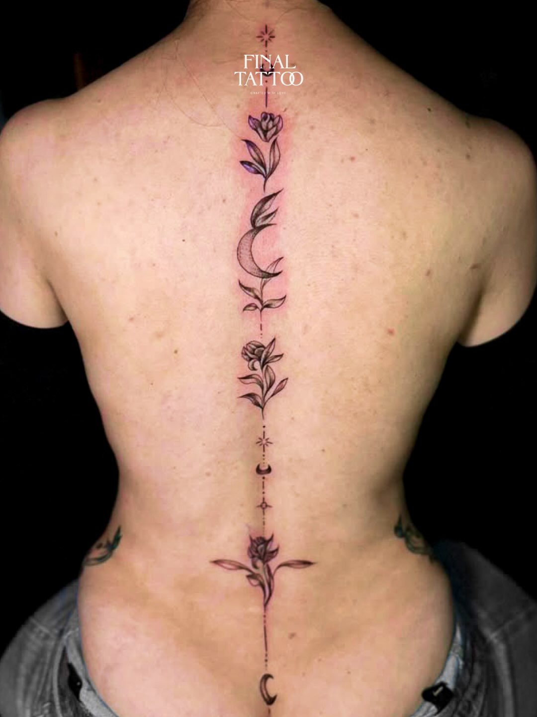A delicate floral and moon spine tattoo